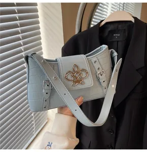 Detail of light blue croc-embossed shoulder bag with a vintage gold floral metal buckle