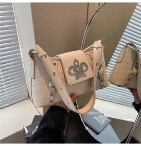 Detail of stone-pattern cream shoulder bag with silver fleur-de-lis metal hardware