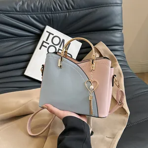 Borsa a secchiello patchwork bicolore con manico in metallo e nappa a cuore