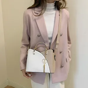 Borsa a secchiello bicolore alla moda con manico dorato circolare e nappa di perle