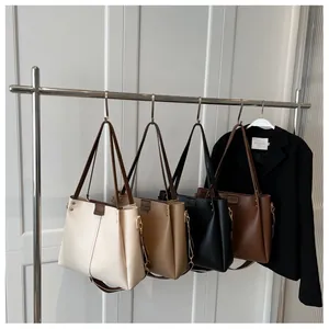 Four elegant minimalist tote bags in cream, khaki, black and brown hanging on a metal rack