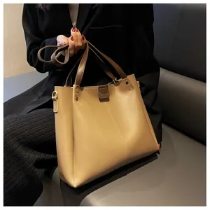 Detail of khaki leather tote bag with wide strap on grey sofa