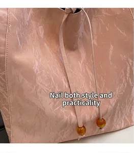 Detalle del bolso rosa con textura arrugada y cuentas de ámbar en el cordón