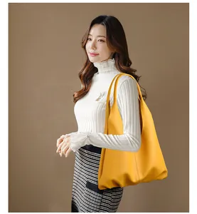 Detailed macro view of the yellow leather texture and handle stitching on the tote bag