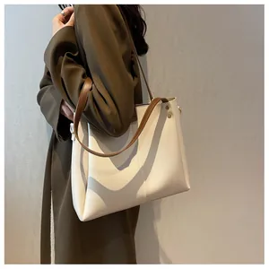 Detail of a large off-white tote bag with brown straps and fine stitching on leather