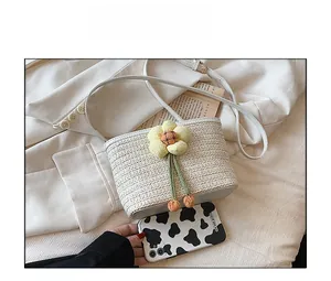Top view of cream woven bucket bag with floral detail and white faux leather strap