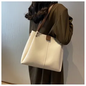 Detail of off-white tote bag with brown straps and logo on premium leather surface
