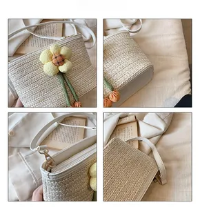 Detail view of woven straw bucket bag with floral decor, zipper and metal hook details