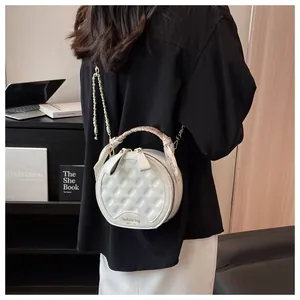 Détail du sac à main blanc matelassé rond avec chaîne dorée et poignée en foulard