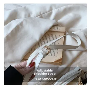 Detail showing adjustable white leather shoulder strap with a fine gold metal buckle