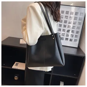 Detail of matte black large tote bag featuring golden metal rivets and vertical stitching