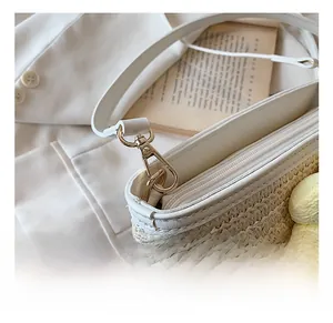 Detail of woven straw bucket bag with white leather strap and gold metal hook