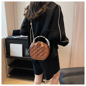 Détail d'un sac rond matelassé marron avec poignée en foulard et chaîne dorée