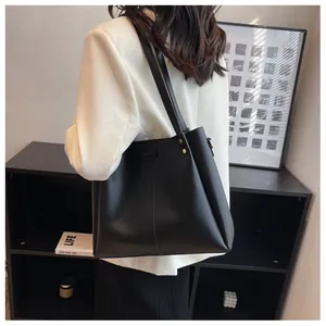 Detail view of a large black tote bag with gold studs and wide shoulder strap style