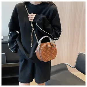 Détail d'un sac rond en cuir matelassé marron avec poignée en soie et bandoulière en chaîne