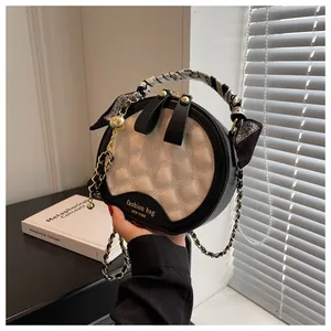 Detail of quilted leather circle bag with silk scarf handle and golden chain strap