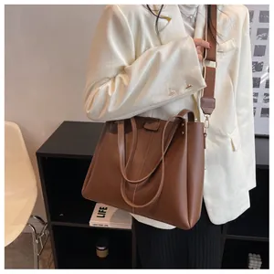 Brown matte leather tote bag detail with wide nylon strap and vertical stitching accents