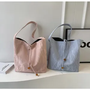 Detalle de bolsos tote minimalistas con textura plisada y cierre de cuentas de ámbar
