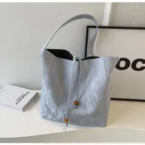 Detalle del bolso tote gris plisado con cierre de cordón y cuentas de resina ámbar