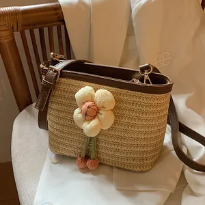 Handwoven straw bucket bag with floral accent and brown faux leather straps for summer