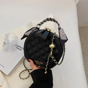 Quilted black round handbag with gold chain strap and silk scarf wrapped handle