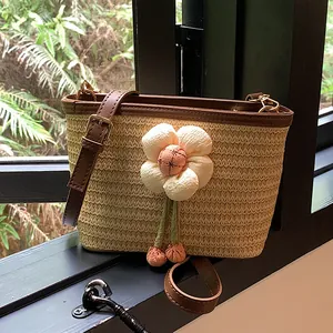Straw bucket bag with large floral decoration and brown leather straps for beach vacation