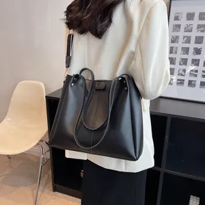 Minimalist black large capacity tote bag with embossed letters worn by a model