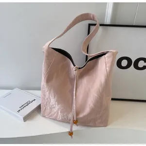 Primer plano del bolso tote rosa plisado rosa con cordón ajustable y cuentas de ámbar