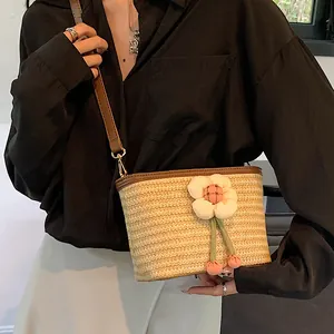 Handwoven straw bucket bag with floral accent and leather strap for beach vacations
