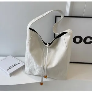 Detalle del bolso tote blanco minimalista con cordón de cuentas de ámbar y forro interior negro