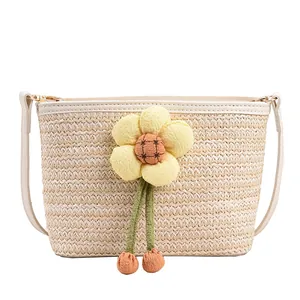 Handwoven straw bucket bag with plush flower charm and leather strap for summer beach vacation