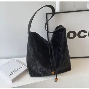 Detalle del bolso tote plisado negro con cierre de cordón y cuentas de ámbar