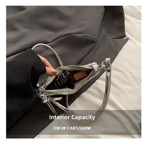 Close-up of the internal capacity of a metallic silver croissant bag showing daily essentials