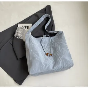 Detalle del bolso tote azul claro con textura plisada y práctico cierre de cordón
