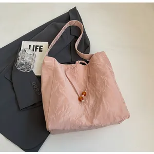 Detalle de bolso tote rosa plisado con textura de tela ligera y cuentas de ámbar