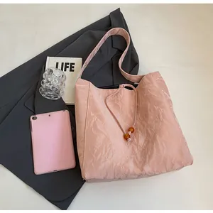 Detalle del bolso tote rosa plisado con cierre de cordón y detalles de cuentas de ámbar
