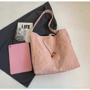 Detalle del bolso tote plisado rosa con cierre de cordón y cuentas de resina decorativas