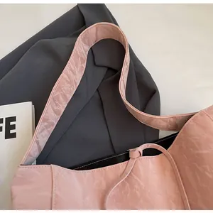 Primer plano de un bolso tote plisado rosa con textura brillante y detalle de cordón