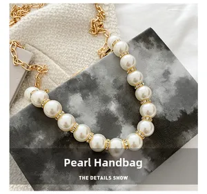 Detailed close-up of pearl handle with gold diamond-encrusted rings on box bag