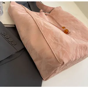 Detalle del bolso tote rosa efecto arrugado con cordón y cuentas de color ámbar