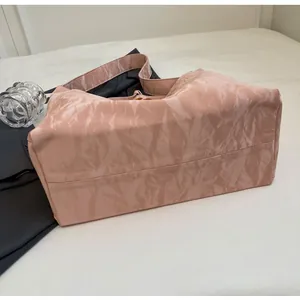 Detalle de bolso tote de satén plisado rosa claro con textura suave y correa ancha