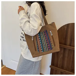 Detail of canvas tote bag with ethnic colorful embroidery and dual metal zippers
