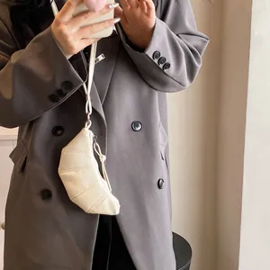 Detail of a creamy white crescent bag with pleated stitching worn by a model