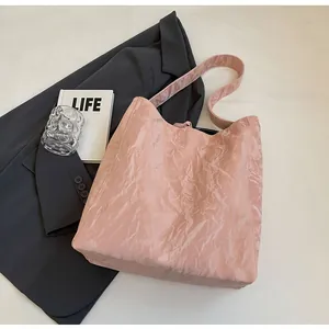 Detalle del bolso tote rosa claro con textura plisada y correa de hombro minimalista