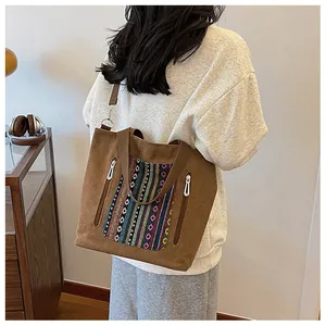 Detail of canvas tote bag featuring ethnic embroidery and side zipper pockets on shoulder