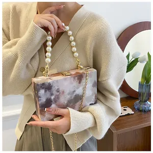 Detail of marble pattern acrylic box bag with pearl handle and gold chain strap