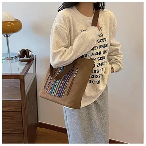 Detail of bohemian canvas crossbody bag with colorful ethnic embroidery and brown strap