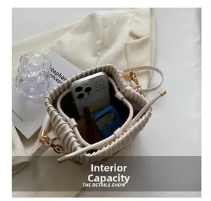 Vue intérieure du sac seau plissé crème montrant la capacité pour téléphone et maquillage