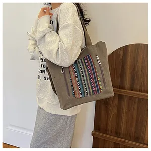 Detail of a large canvas tote bag with ethnic embroidery and functional zippers