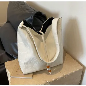 Detalle de bolso tote blanco plisado con cuentas de ámbar y detalles de nudos